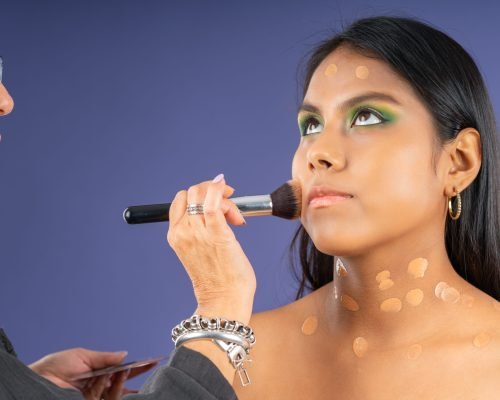 Applying foundation to young model, on a purple background